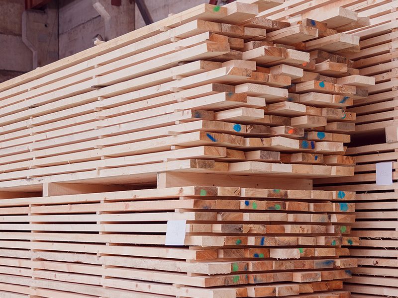 Warehouse or factory for sawing boards on sawmill indoors. Wood timber stack of wooden blanks construction material. Logging Industry.